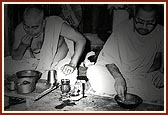 Swamishri having dinner in the light of a small oil lamp at the house of Purushottam Shivdas, January 1976, Sakore