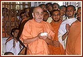 Swamishri with a ball of flowers in hand