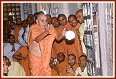 Swamishri offers the flower ball at the feet of Shri Harikrishna Maharaj