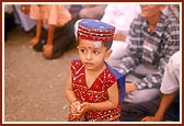 A little boy, dressed for the occasion, listens attentively to Swamishri's blessings