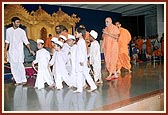 Children lead Swamishri from the assembly hall