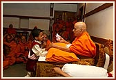 Swamishri talks to the child, gives him prasad...