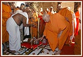 Swamishri applies chandlo to a balak during a sugar-weighing ritual (sakar tula)