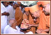 Swamishri presents Shri Harikrishna Maharaj for darshan to Shri Pruthvisinh Bapu - an old, ailing devotee