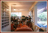Swamishri performs his morning puja indoors in the confined space of a house because it was raining outside