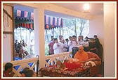 Swamishri performs his morning puja indoors in the confined space of a house because it was raining outside