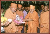 Swamishri offers a lotus garland to Shri Harikrishna Maharaj