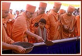 Swamishri pours cement into the foundation pit 