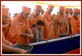 Swamishri pours cement into the foundation pit 