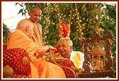 Swamishri sprays the sanctified colored water on a leading devotee