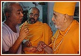 The pujari of the mandir narrates the history and glory of the murtis to Swamishri