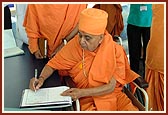 Swamishri writes his blessings in the guest book