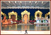 Swamishri bows to the assembly with the sinhasans for BAPS mandirs in Chicago and Houston in the backdrop