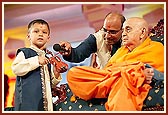 Swamishri asks the child to play the mini violin