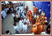 Swamishri sanctifies the asthi (ashes) of a devotee, prior to its immersion in river Gondali with flowers and rice grains offered to Shri Harikrishna Maharaj