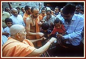Swamishri initiates (vartman) a child
