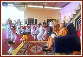After his puja Swamishri participates by playing 'ghughra' while devotees of Badalpur sing bhajans