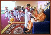 After his puja Swamishri participates by playing 'ghughra' while devotees of Badalpur sing bhajans