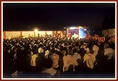 Swamishri blesses the volunteers of the tribal areas during an assembly held in the compound of 'Pramukh Paper Products'