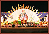 "Suraj Sahajanand..." Swamishri during the Hari Jayanti festival with an attractive backdrop of Bhagwan Swaminarayan and the rising sun that dissolves all darkness