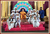 Children dressed as seniors with Swamishri after presenting a debate