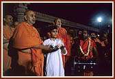 Enjoins Yogi, a balak from USA, in performing arti of Thakorji