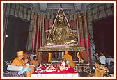 Swamishri performs mahapuja before the beautiful murti of Bhagwan Swaminarayan, which is suspended three foot above its seat to allow the placement of auspicious articles in the pit under the murti