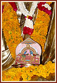 Shri Harikrishna Maharaj in the lap of the grand murti of Bhagwan Swaminarayan