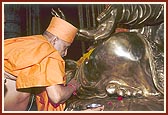 Swamishri performs pujan by doing chandlo on the holy feet of the murti