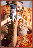 To see the intricate carvings, a youth zooms with his video camera and shows it to Swamishri on the LCD monitor