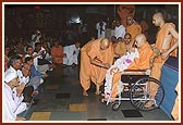Despite ill health Swamishri never misses going to Thakorji for darshan. Today, while on his way for darshan, Pujya Tyagvallabh Swami offers a garland of rakhdis on behalf of all the devotees