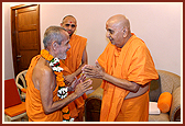 Swamishri welcomes Pujya Vishveshtirthji, Head of Pejawar Muth, Bangalore, with a garland