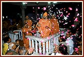 Swamishri blesses devotees participating in the abhishek rituals by showering flower petals