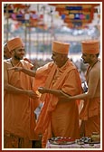 Swamishri blesses devotees by showering rice grains