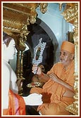 ... Swamishri holds a mirror during mukh darshan ritual