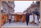 Despite the monsoon rains Swamishri takes his daily morning round for Thakorji's darshan. Devotees eagerly await for Swamishri's darshan in the rain 
