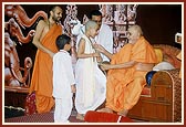 Swamishri gives janoi to a child