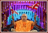 Swamishri waves a BAPS flag for the Sanstha's Centenary Celebration