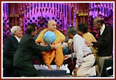 Senior devotees present a globe to Swamishri with a prayer of peace to prevail in the world