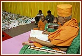   Swamishri writes his blessings in the account book